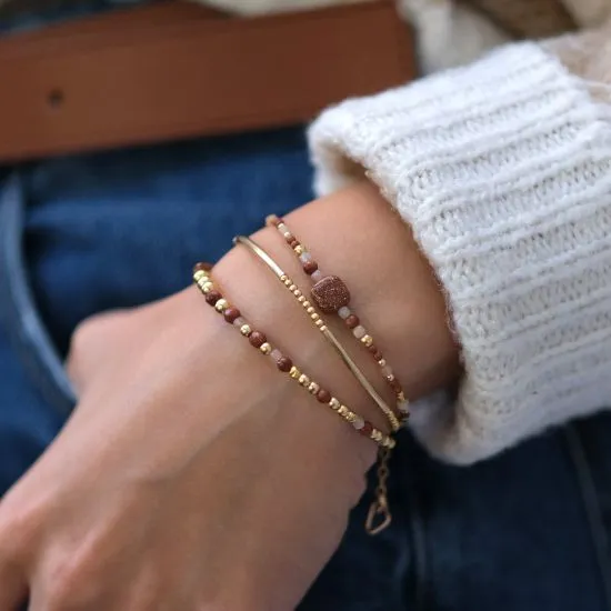 Poignet portant plusieurs bracelets fins en or laminé et pierres