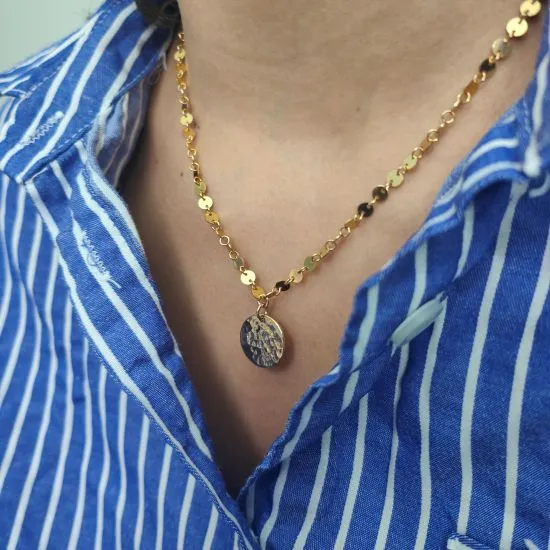 Collier fin en or laminé porté sur une chemise rayée bleue